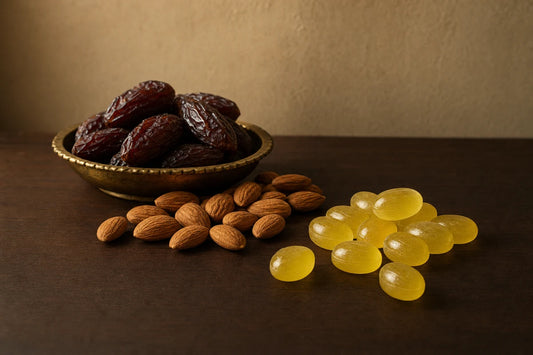 A brass dish of dried dates with almonds and lemon coloured boiled sweets on a dark walnut table